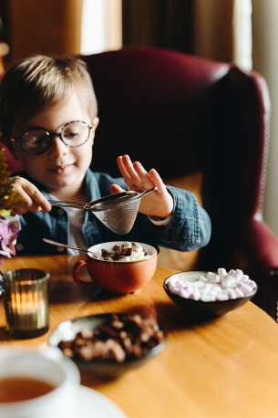 Hôtel Ermitage, 4 étoiles à Evian - Enfant préparant son chocolat chaud en saupoudrant de cacao