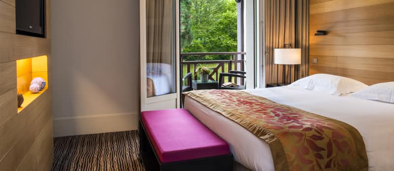 Suite Junior Sud de l'Hôtel Ermitage avec la bain vitrée ouverte sur le balcon en face du parc