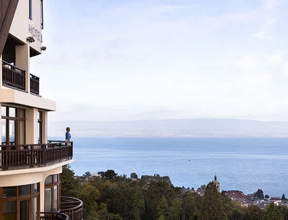 Une femme au balcon du 5ème étage de l'Hôtel Royal avec la vue sur le lac Léman