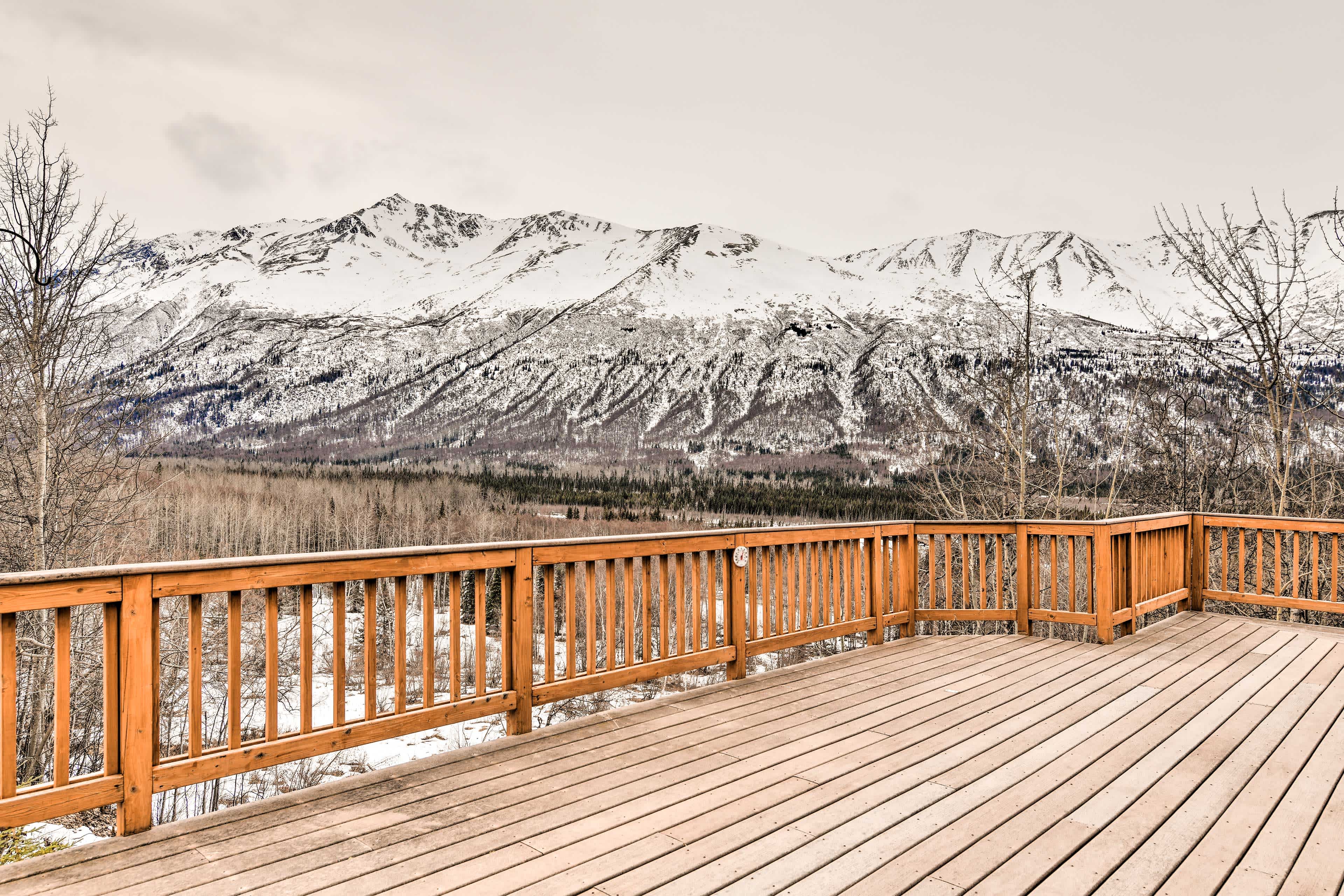 View of snowy mountains from a wooden deck in Anchorage, AK