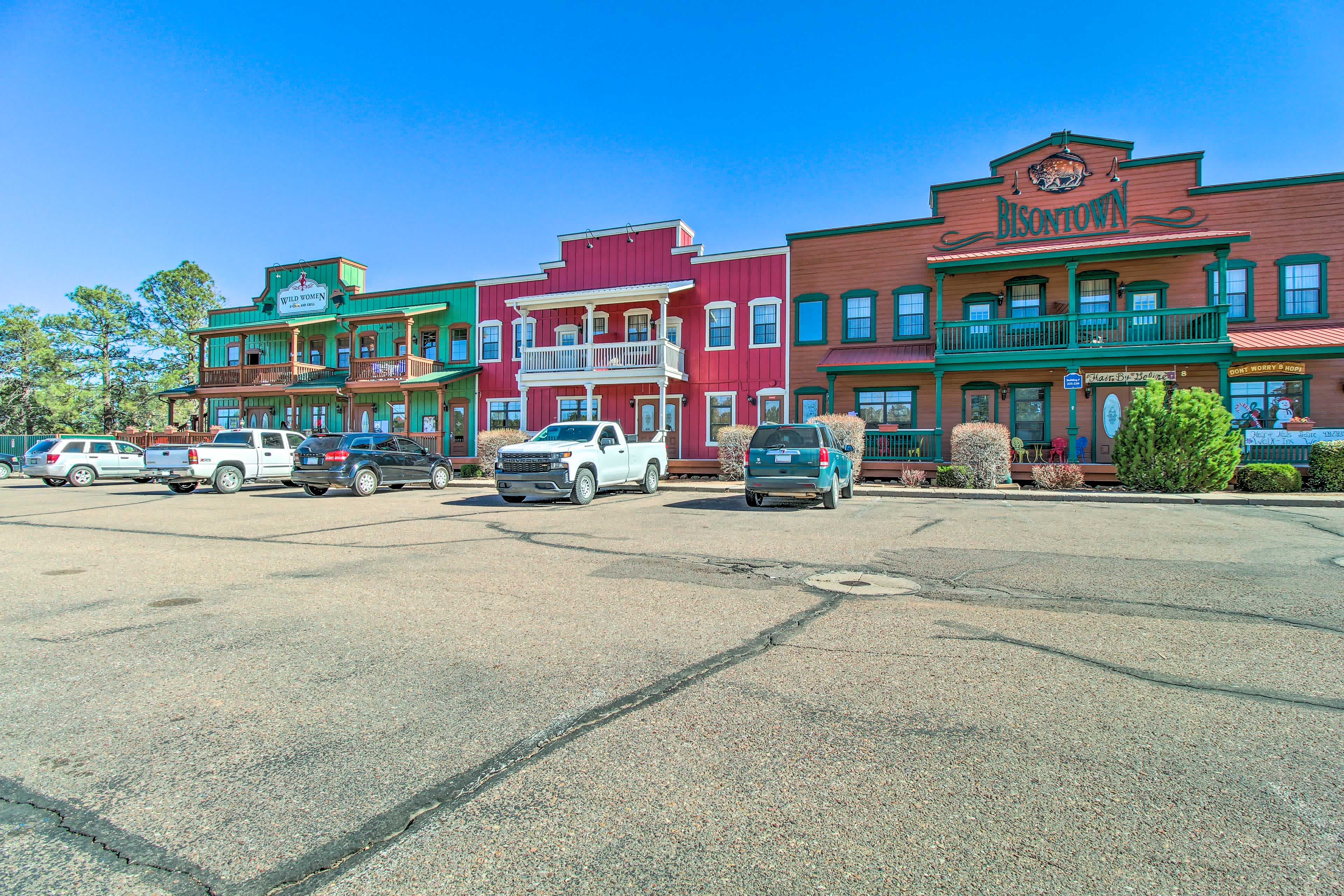 View of a strip of old fashioned buildings with cars parked in the front and blue skies overhead in Overgaard, AZ