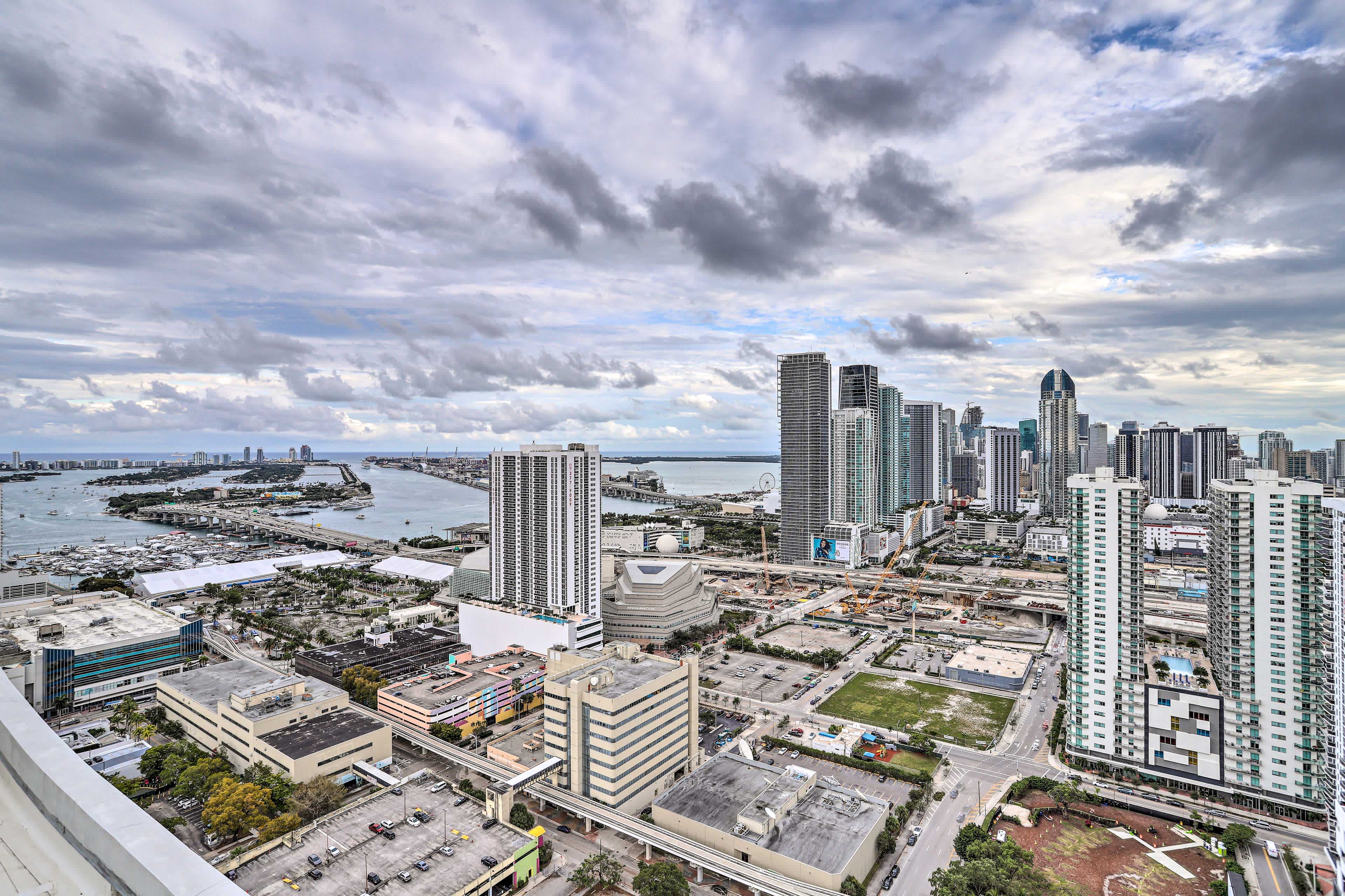 Aerial view of downtown buildings in Miami, FL with canals in the background, and a cloudy blue sky