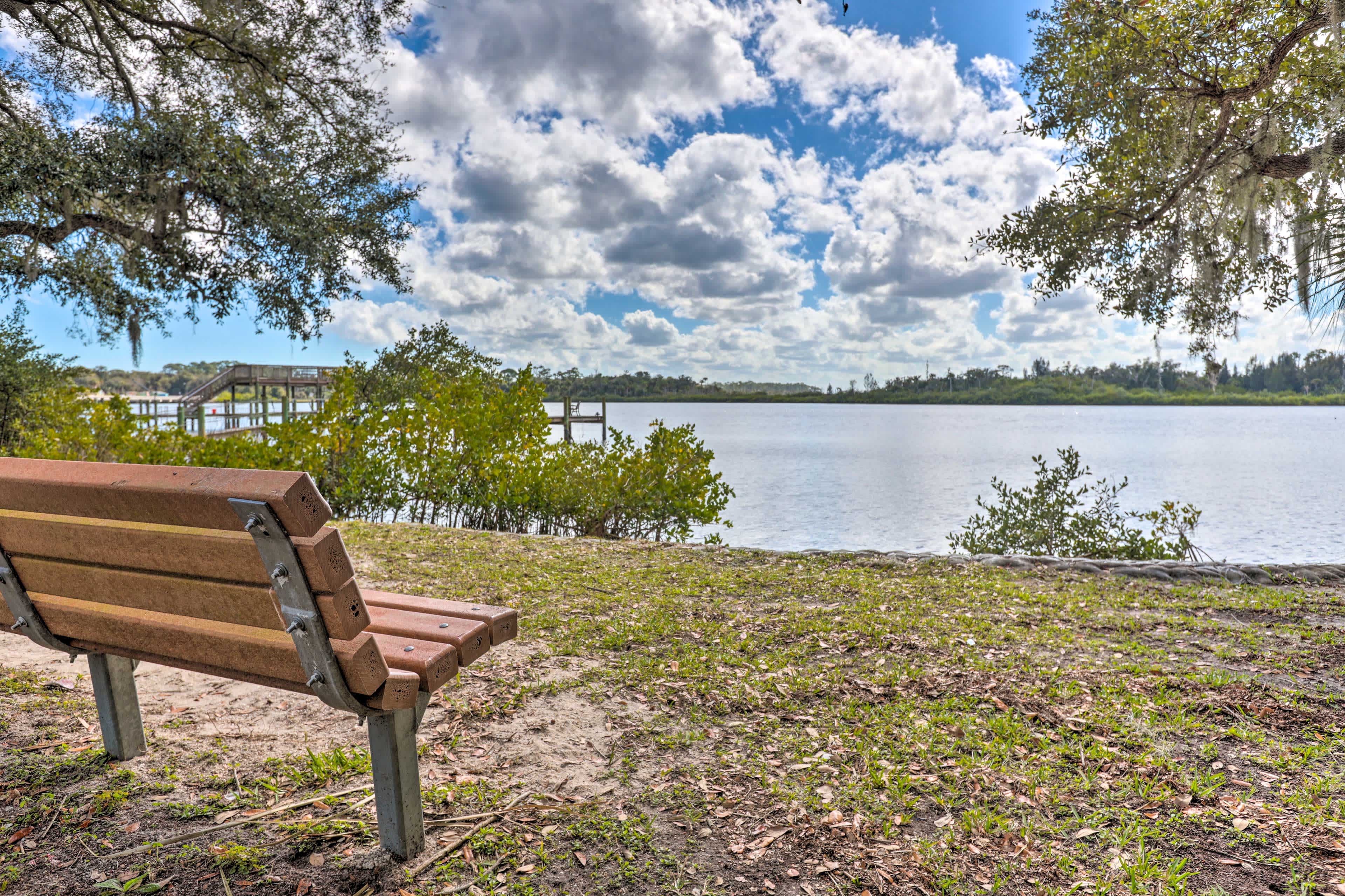 View of a park bench in Port Orange, FL with a lake and blue skies with clouds