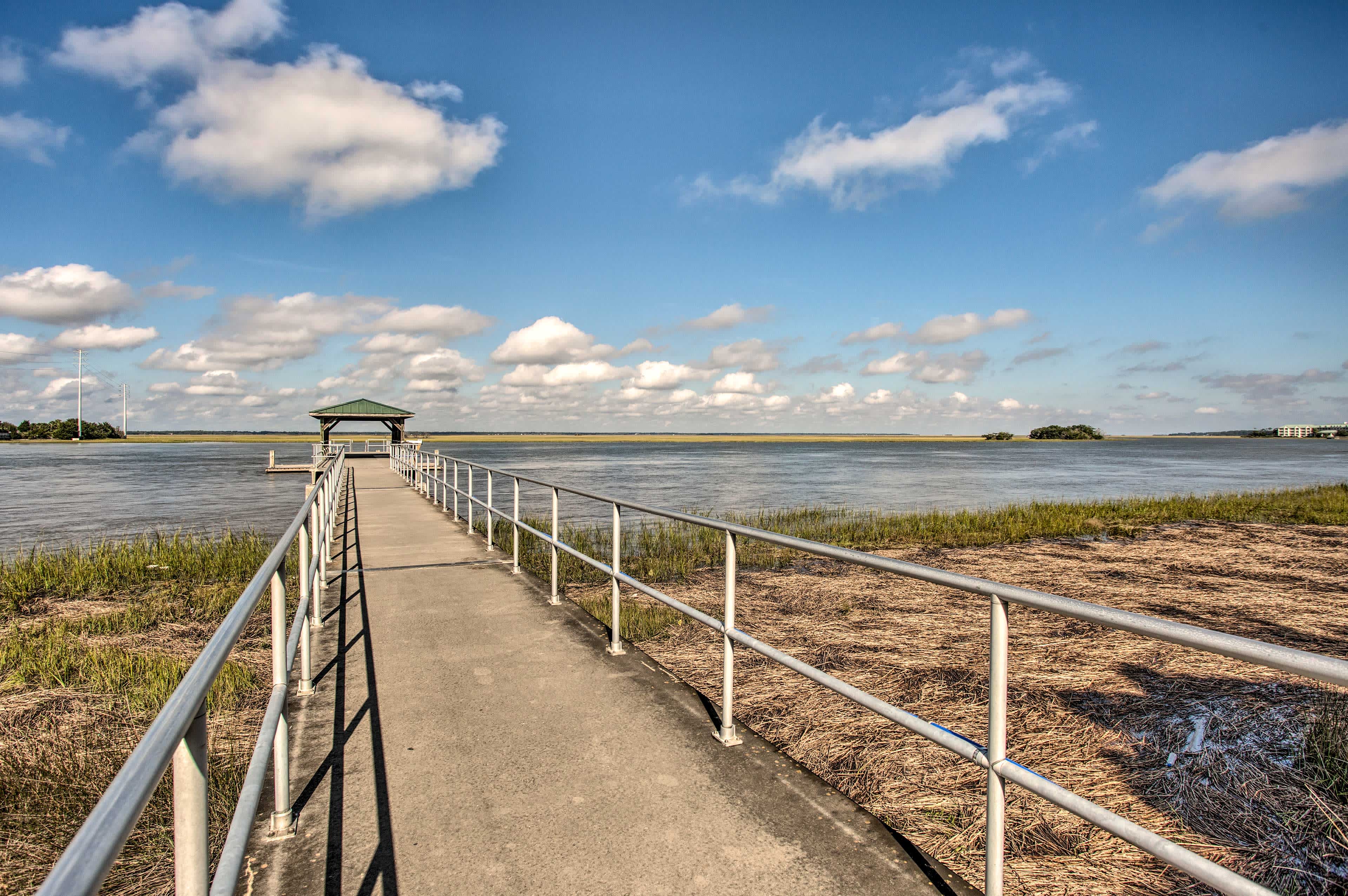 Cement walkway going out into a lake with blue skies overhead in St. Simmons Island, GA