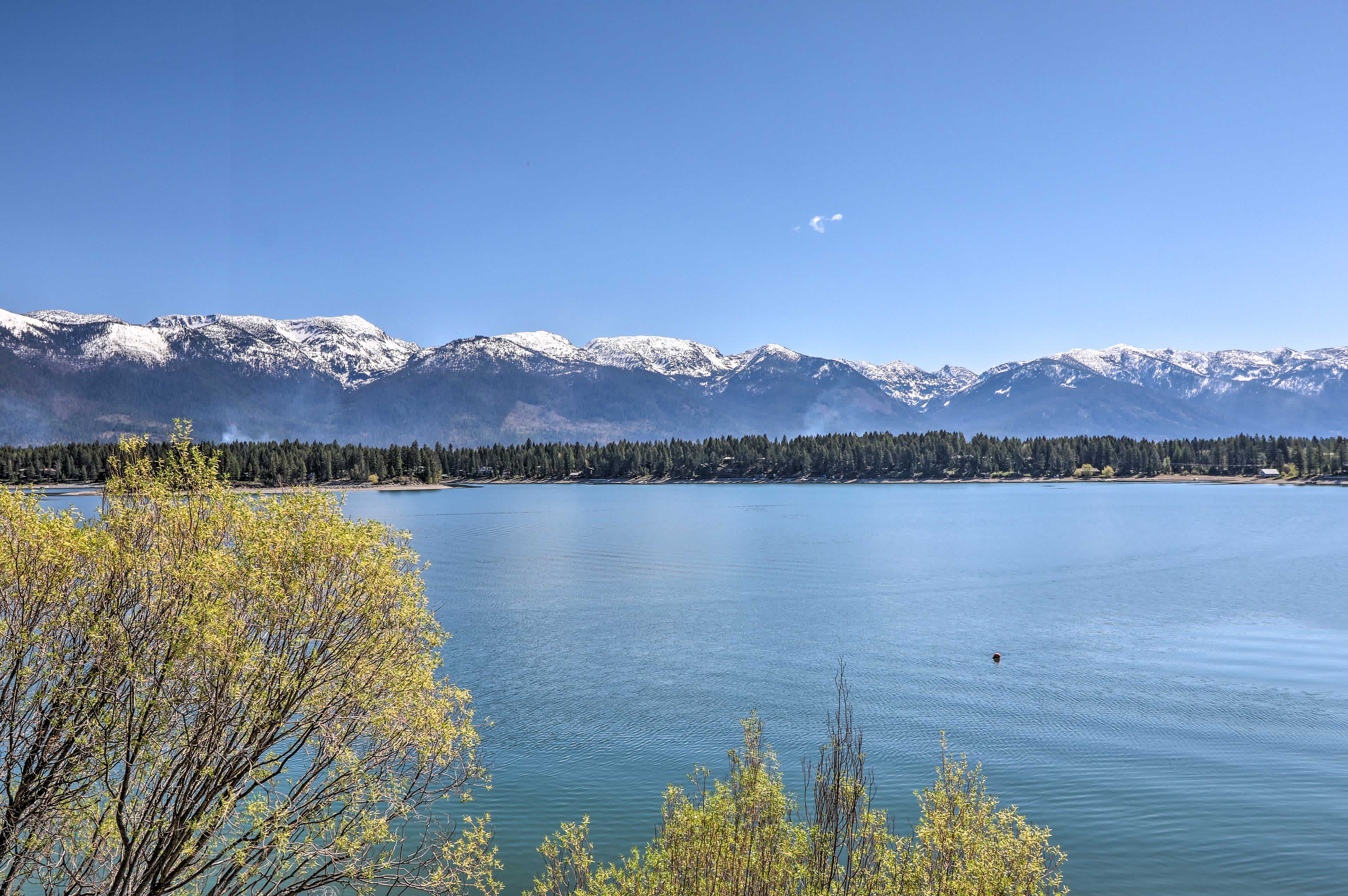 View over a lake in Bigfork, MT with a mountain view in the background and blue skies overhead