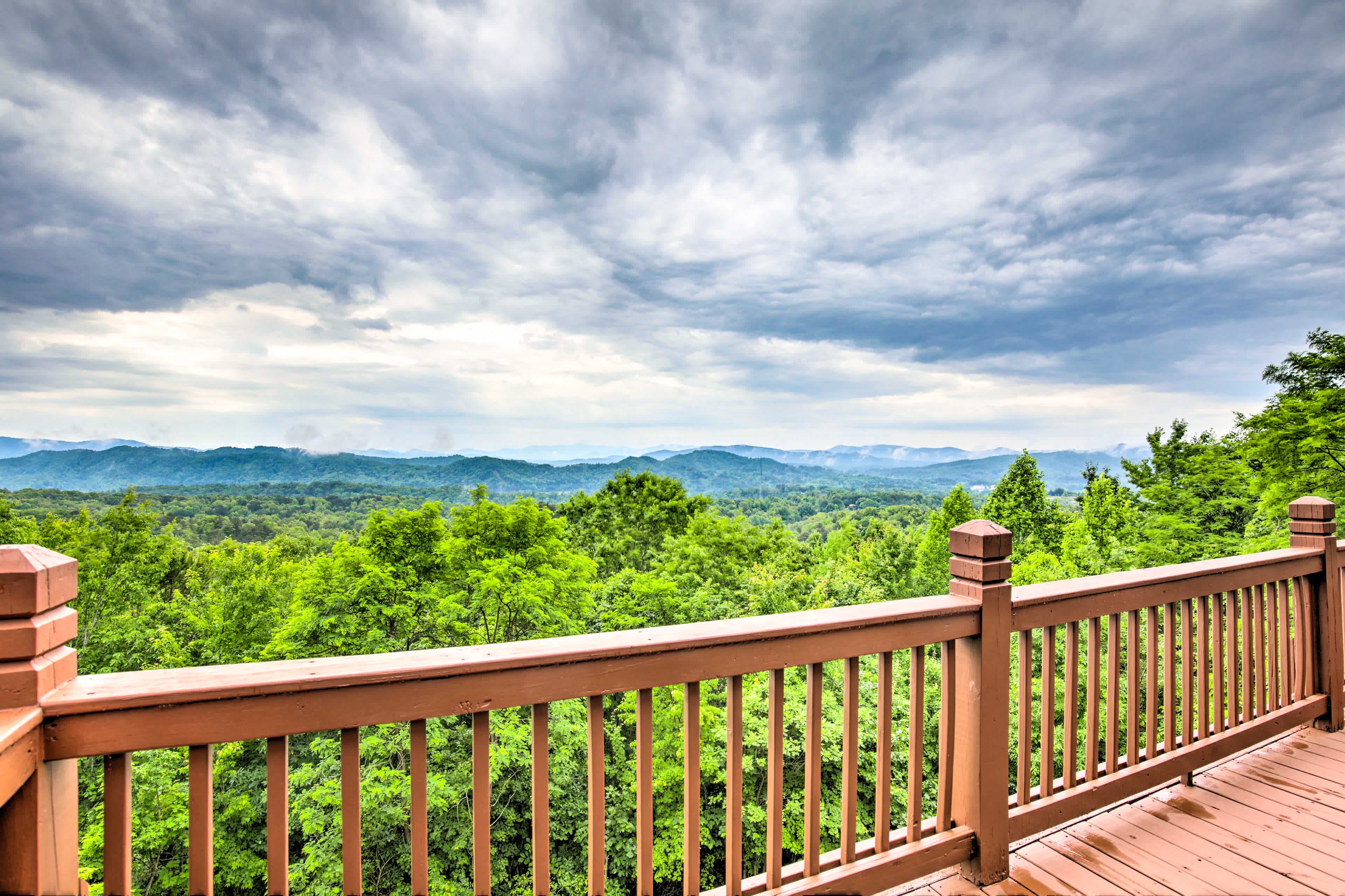 View of a forest and mountain scene in Murphy, NC from a balcony with a wooden fence in the foreground