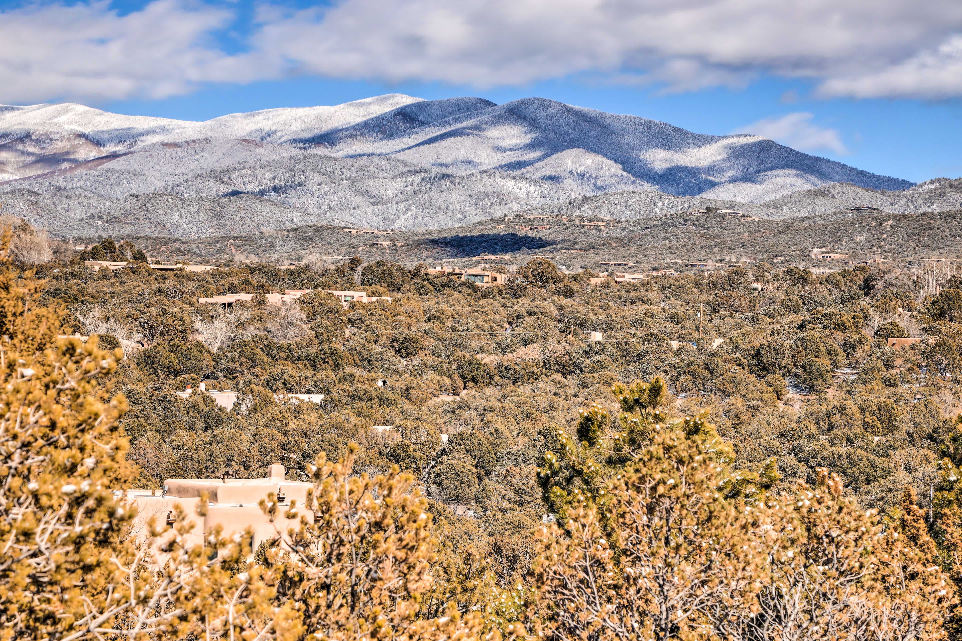 View of mountains in Santa Fe, NM with greenery in the foreground and frosted mountains in the background