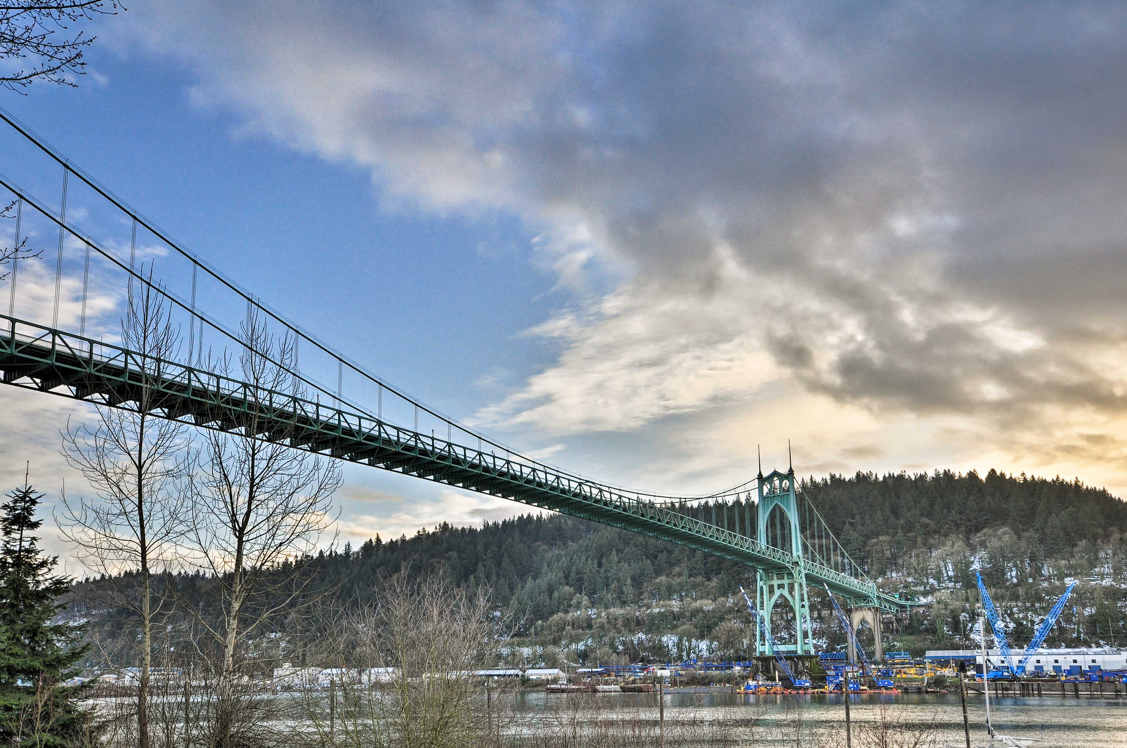 Bridge over a river in Portland, OR with the sun setting in cloudy skies