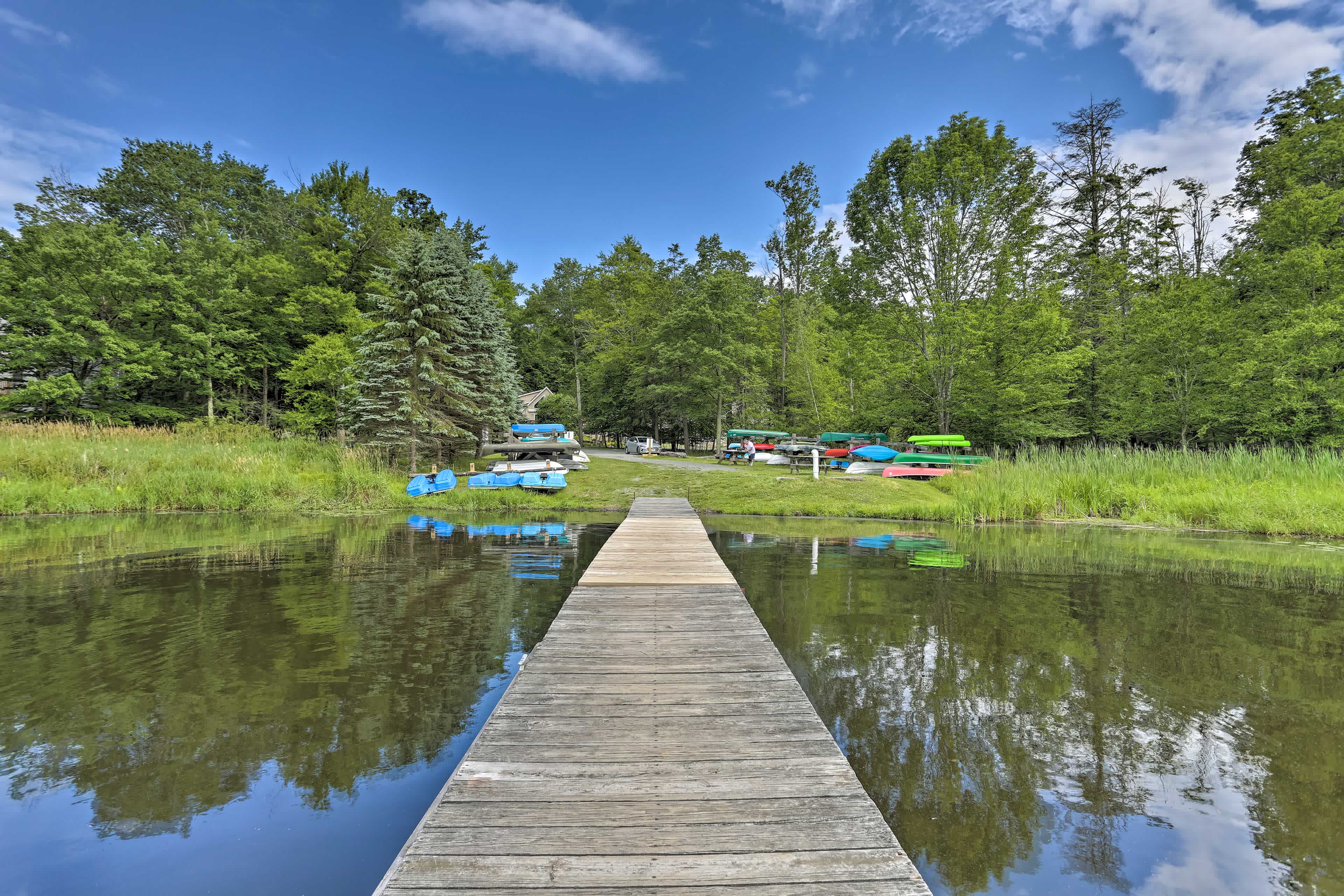 View from the end of a wooden dock in Lake Ariel, PA looking in at a shore with canoes