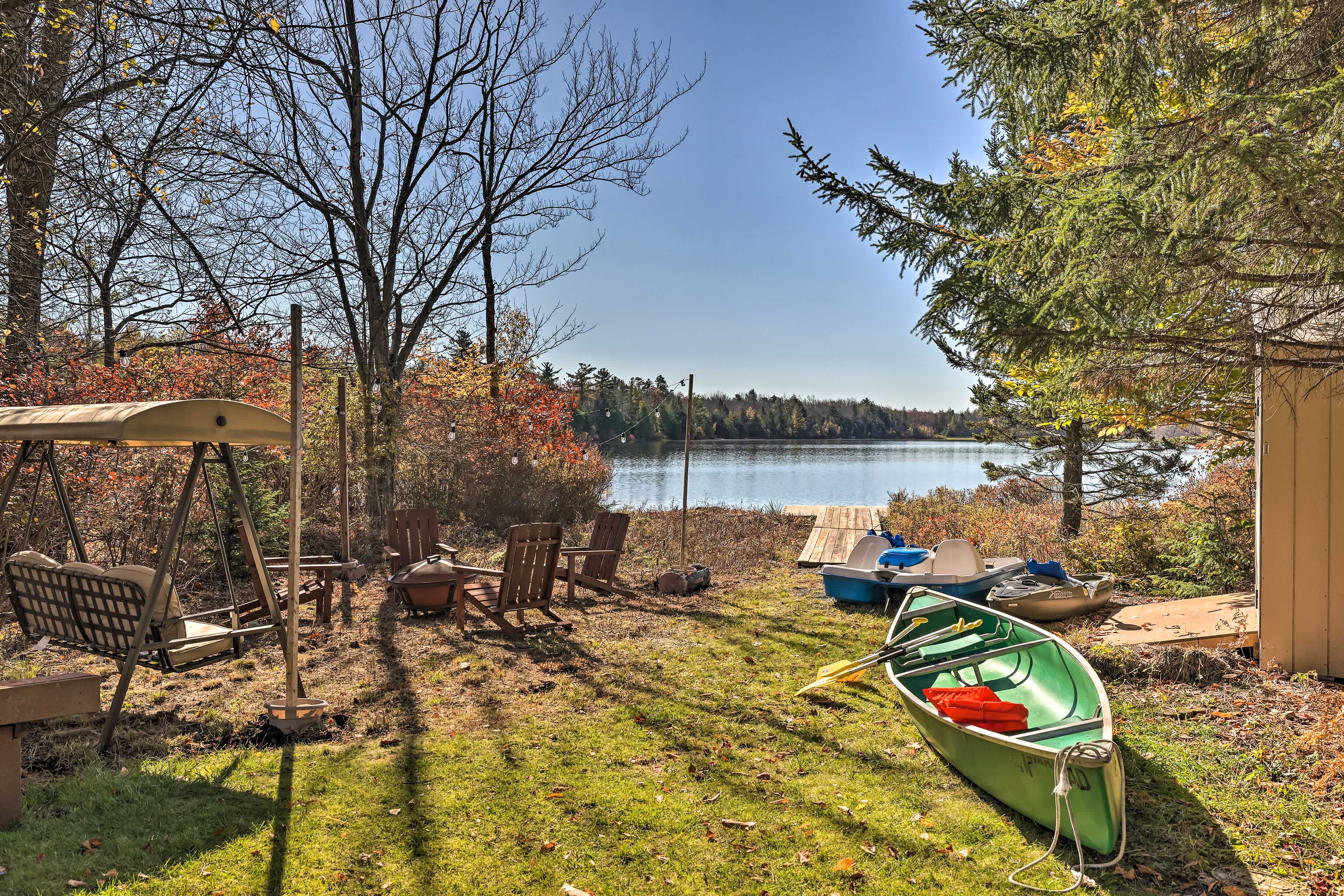 View of a lake with mixed fall forestry including an outdoor lounge area along with boating gear at Pocono Summit, PA