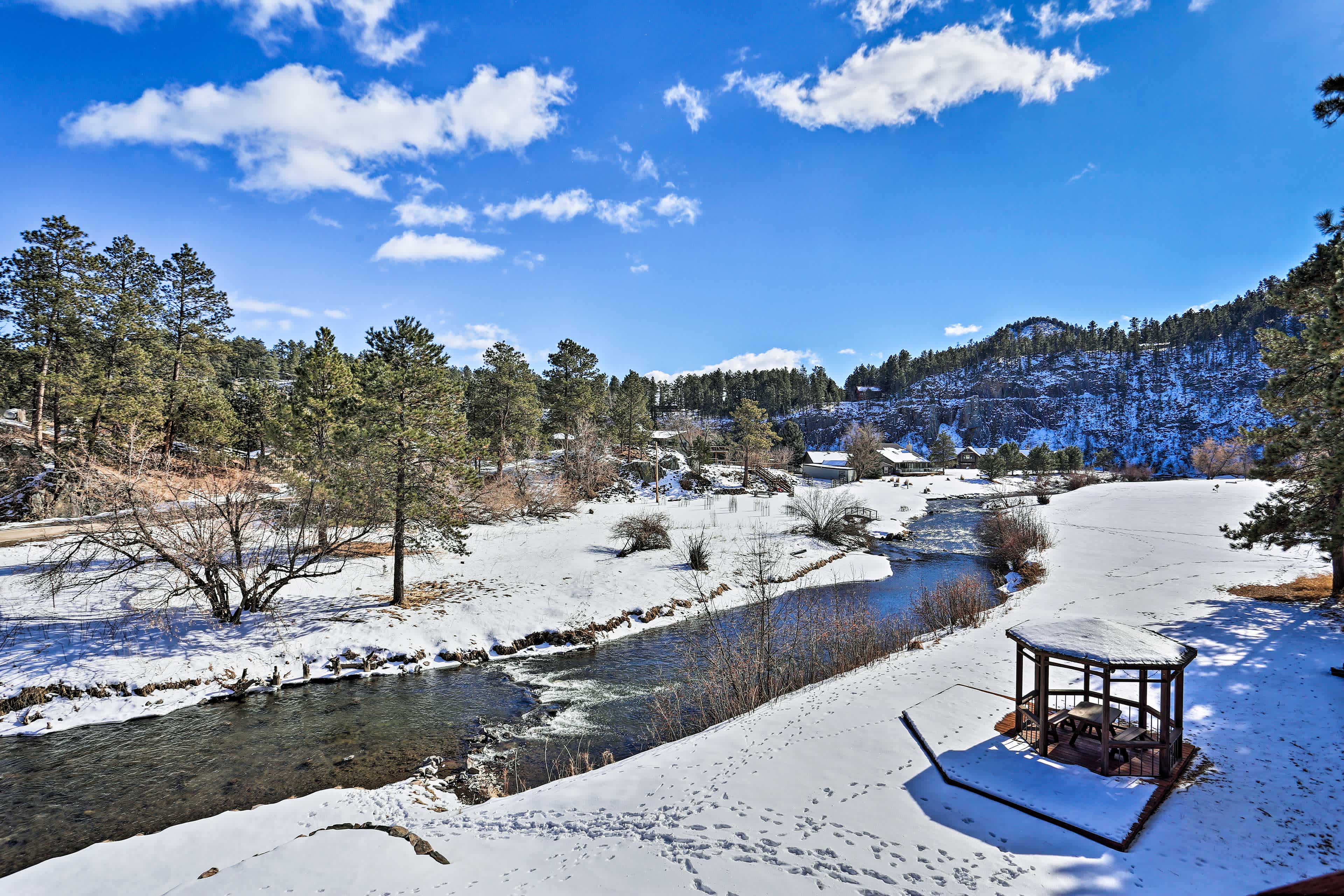 Snowy scene of Rapid City, SD with a winding river and evergreen filled hills