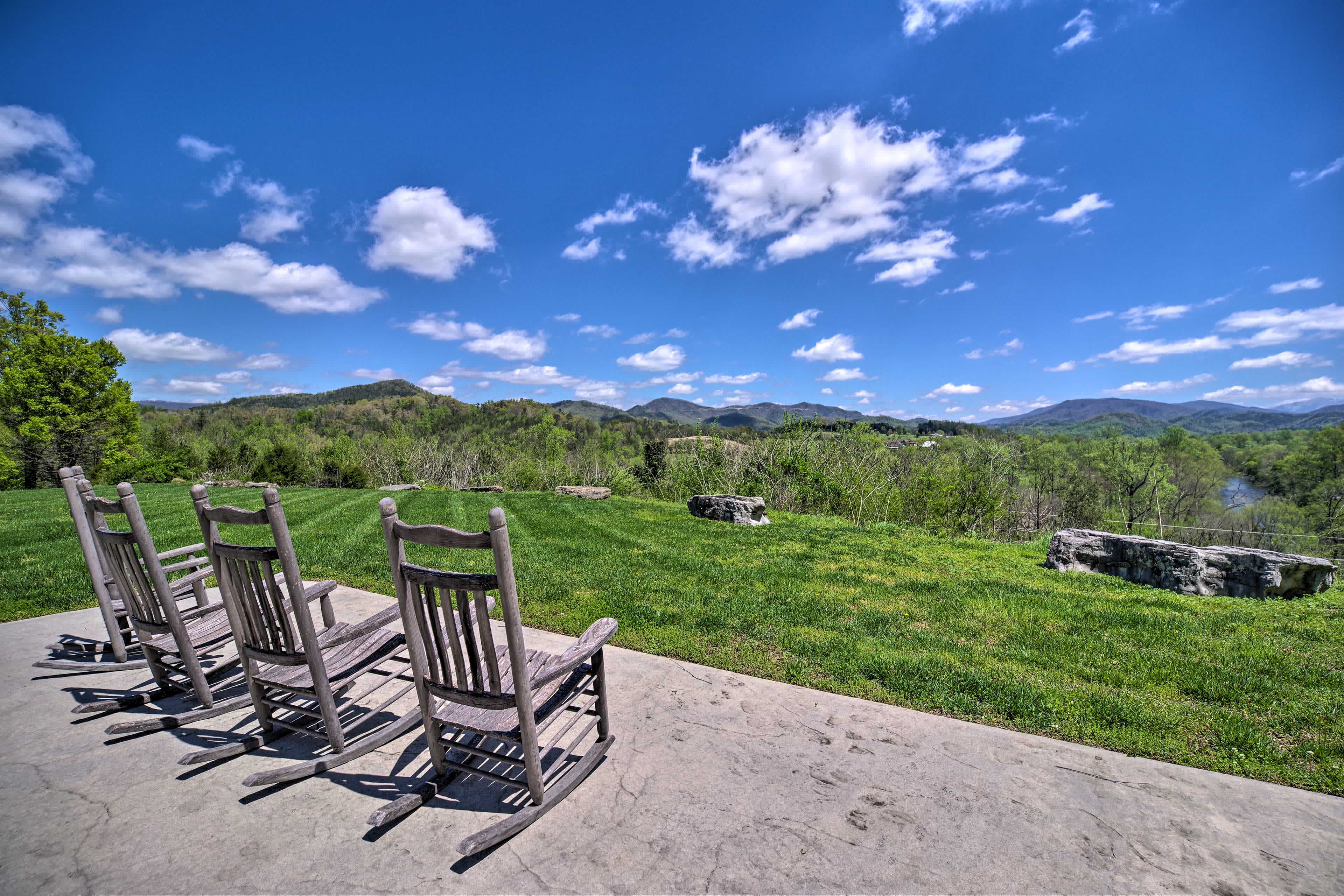 Landscape view of Townsend, TN with wooden chairs in the foreground and green mountain views in the distance with blue skies above.