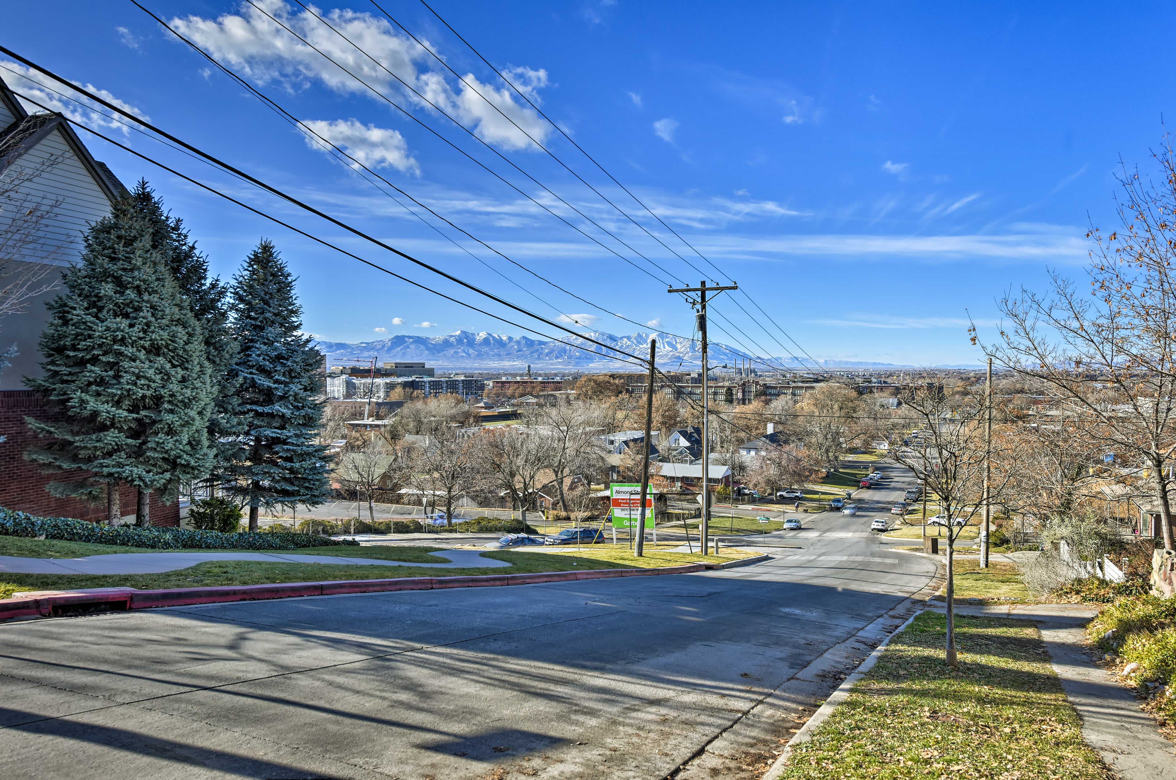 View of a suburban road in Salt Lake City, UT with houses and powerlines and mountains in the background