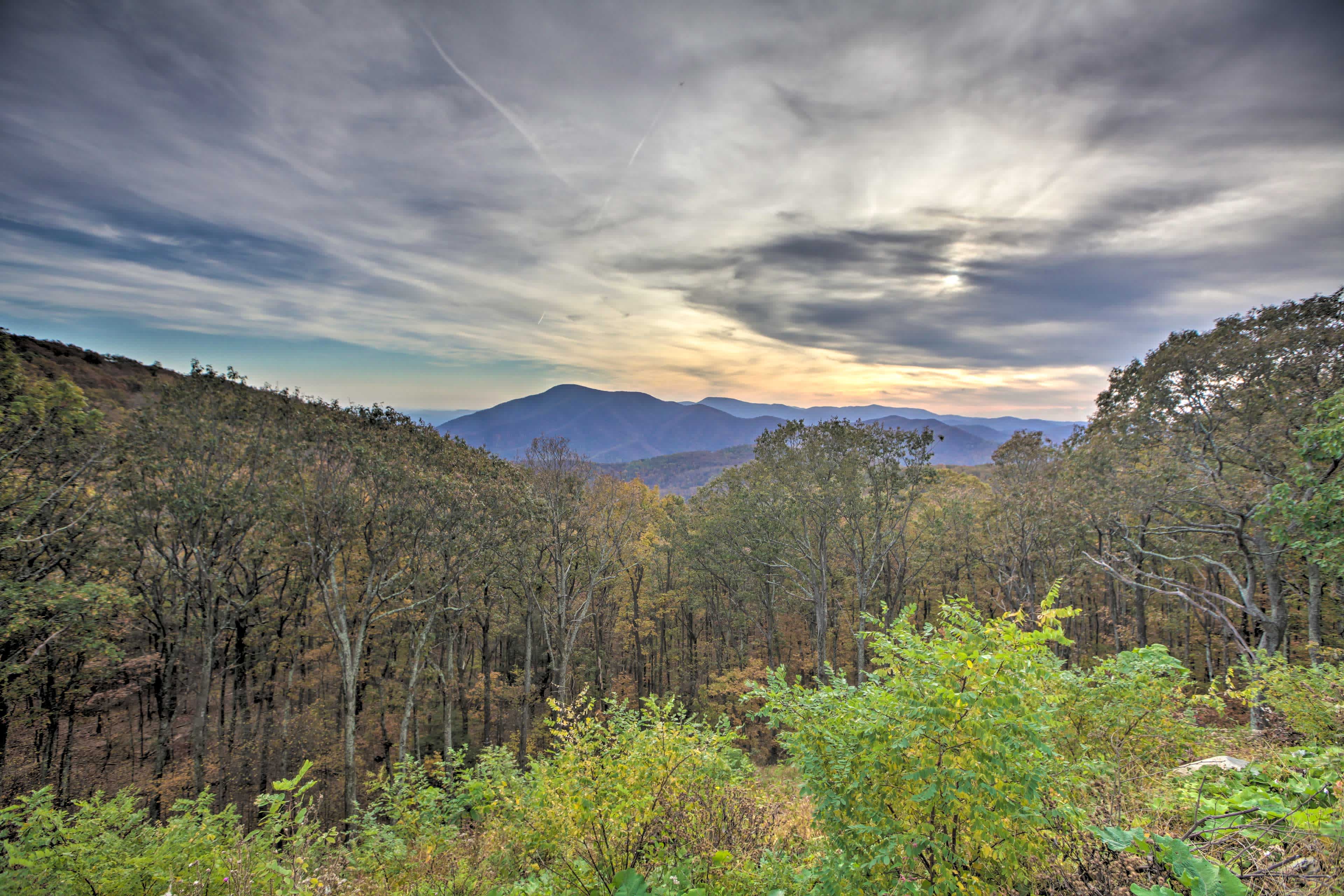 View of a sunset over a mountain range in Roseland, VA with forest trees in the foreground