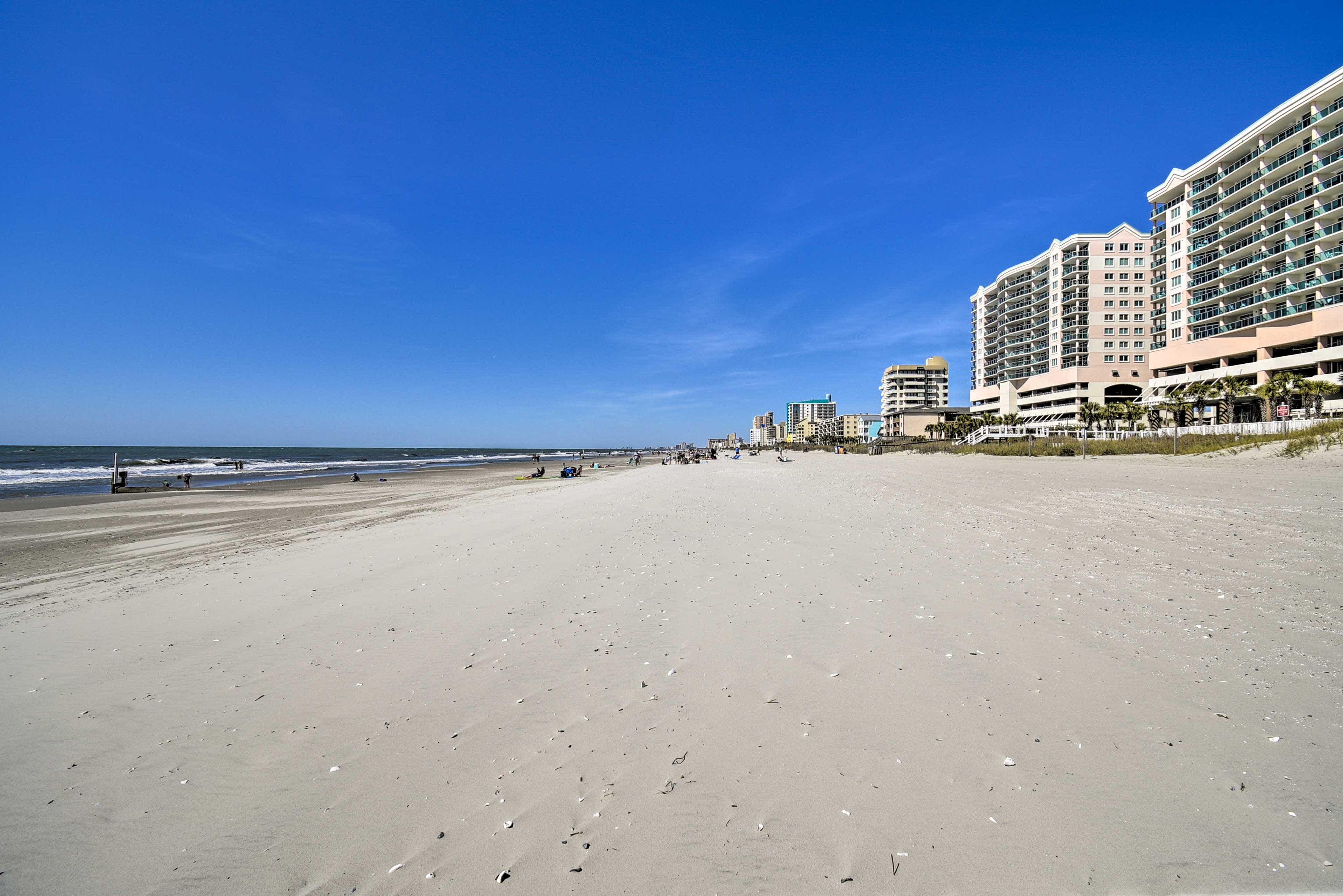 View of a row of condos on the beach by the ocean with blue skies