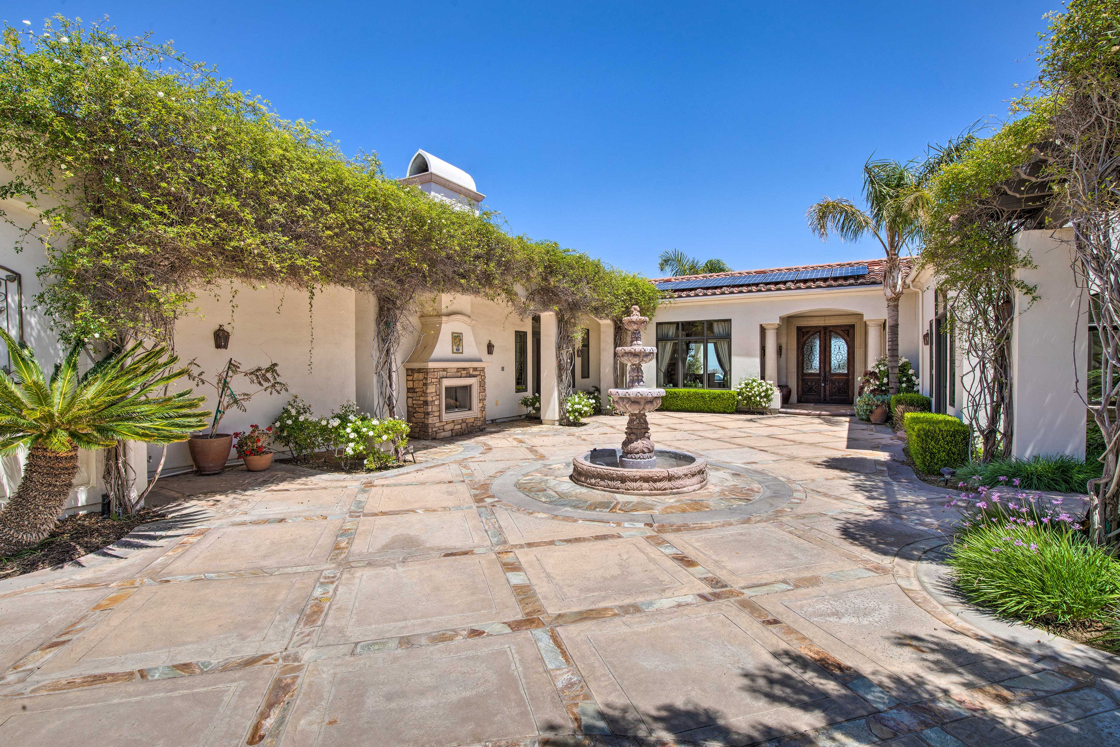 Villa courtyard with a fountain at the center, vines climbing on the walls, and an outdoor fireplace