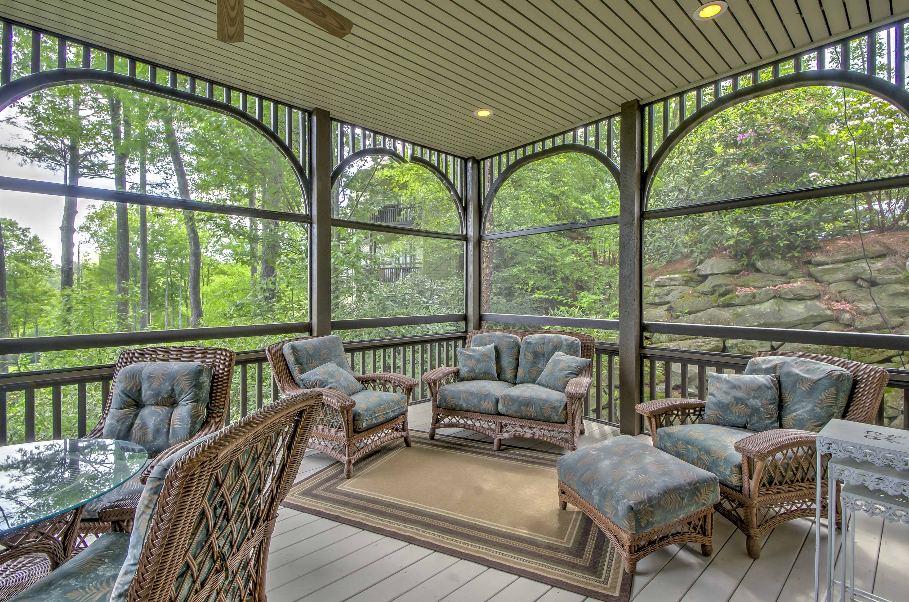 The condo features a spacious screened-in porch with plenty of comfortable furniture.