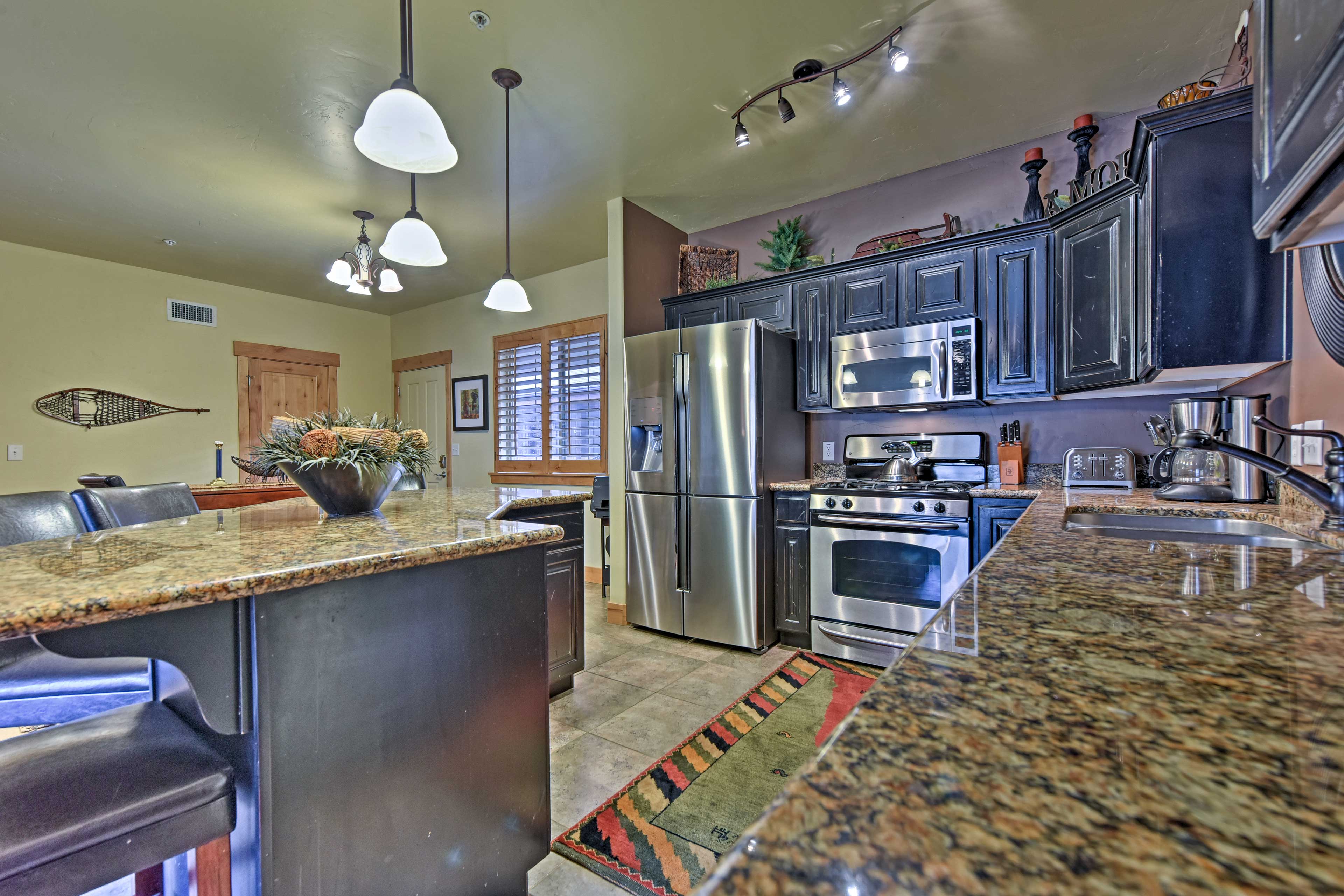 The kitchen features stainless steel appliances, black cabinets and an island.