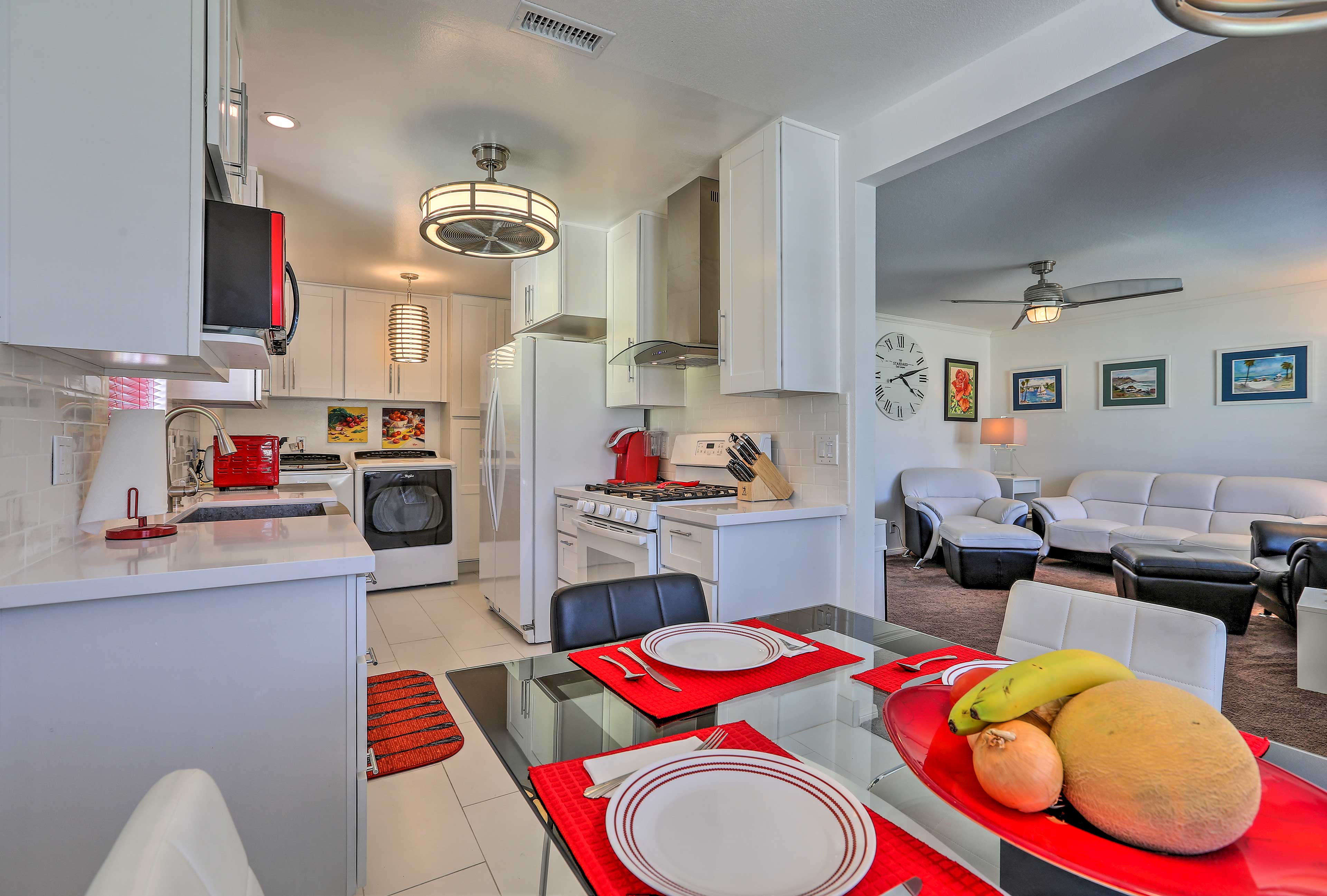 Red appliances and decor accent the white-themed dining and kitchen areas.