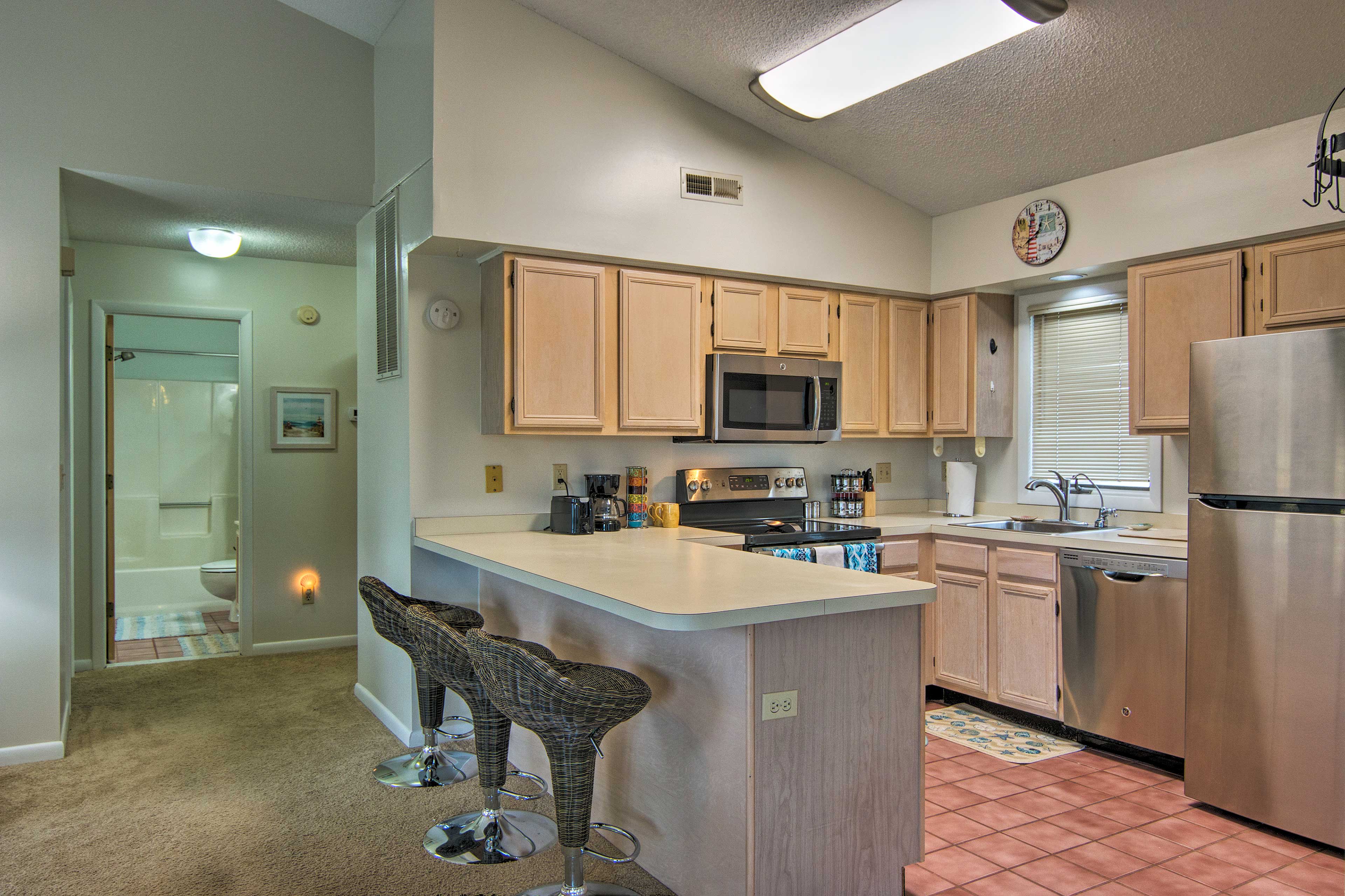 Tiled floors and a peninsula with bar stools furnish the fully equipped kitchen.