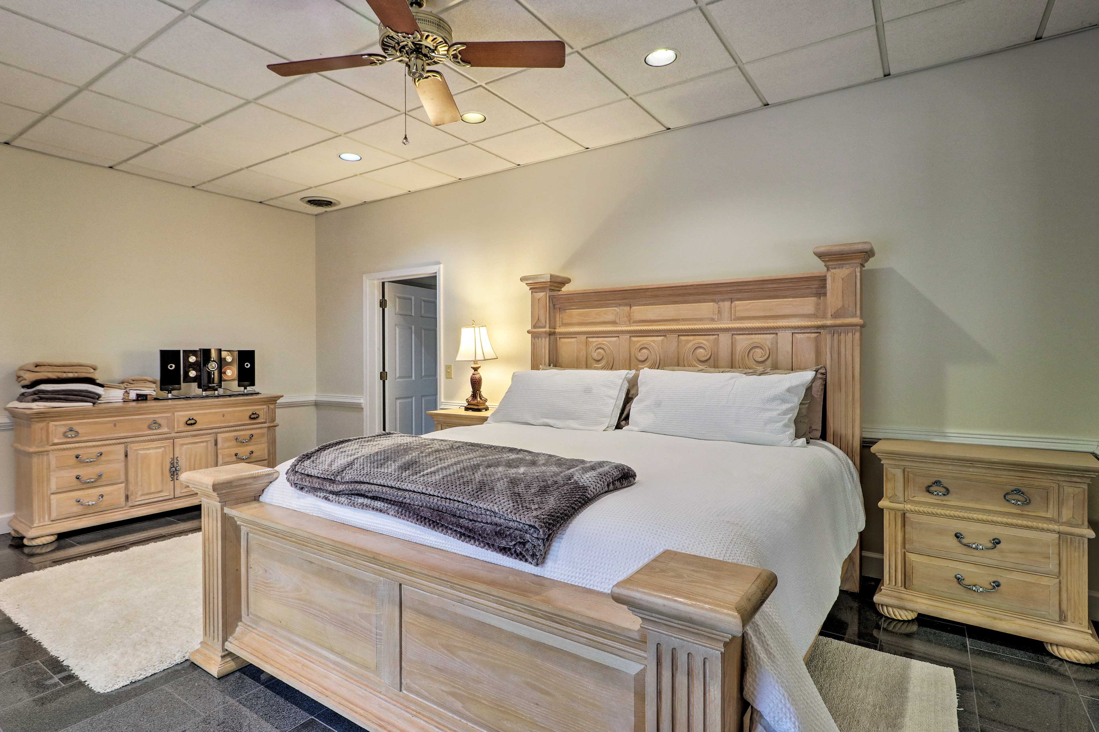 This bedroom hosts a queen bed set on a grand wooden bedframe.