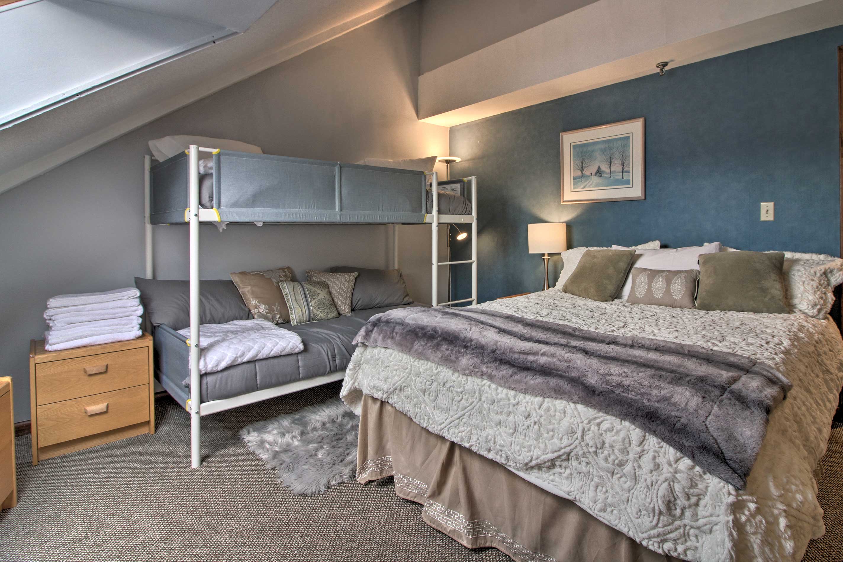 The bedroom offers a queen bed and twin bunk beds.