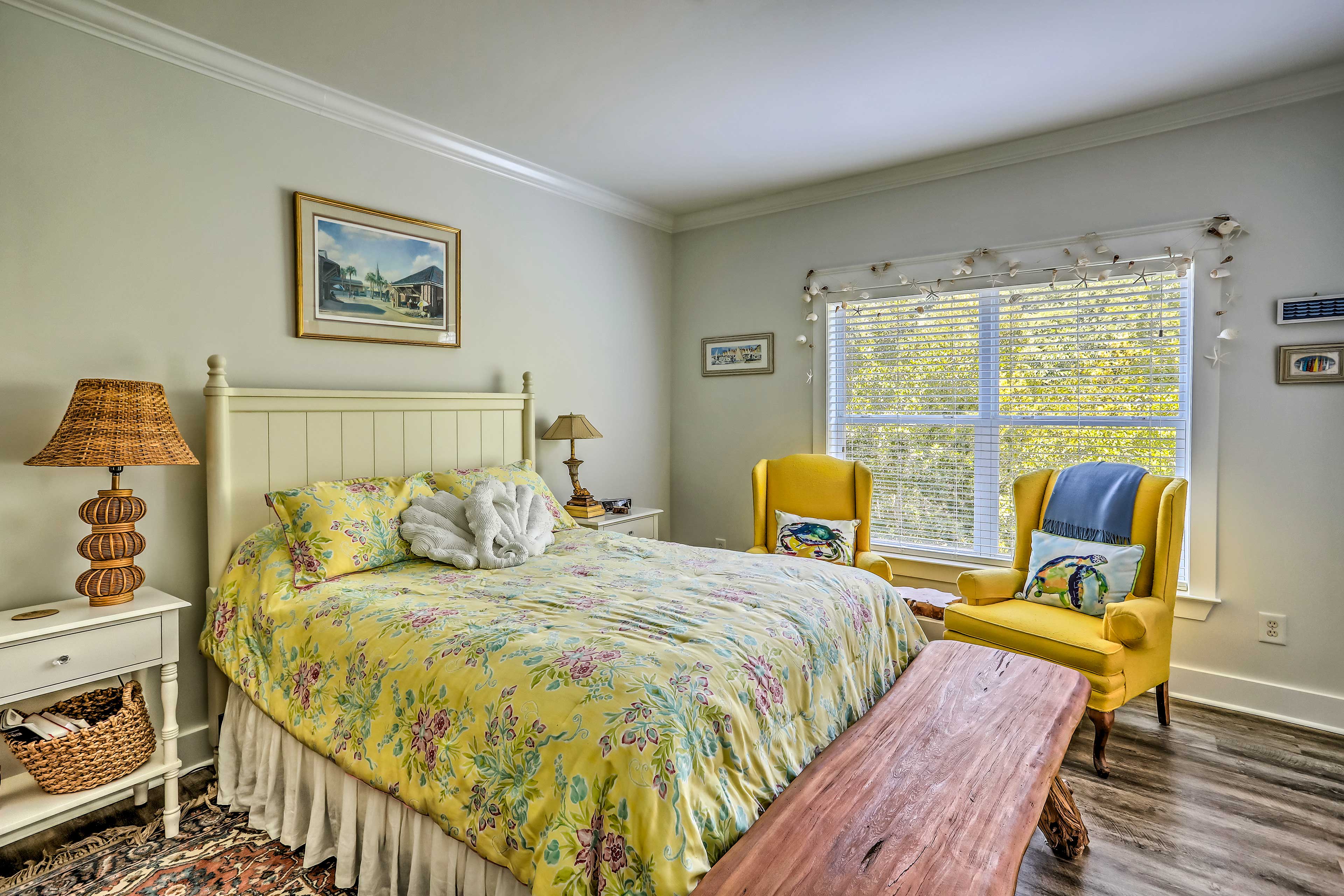 This sunny bedroom features a queen bed and 2 reading chairs.