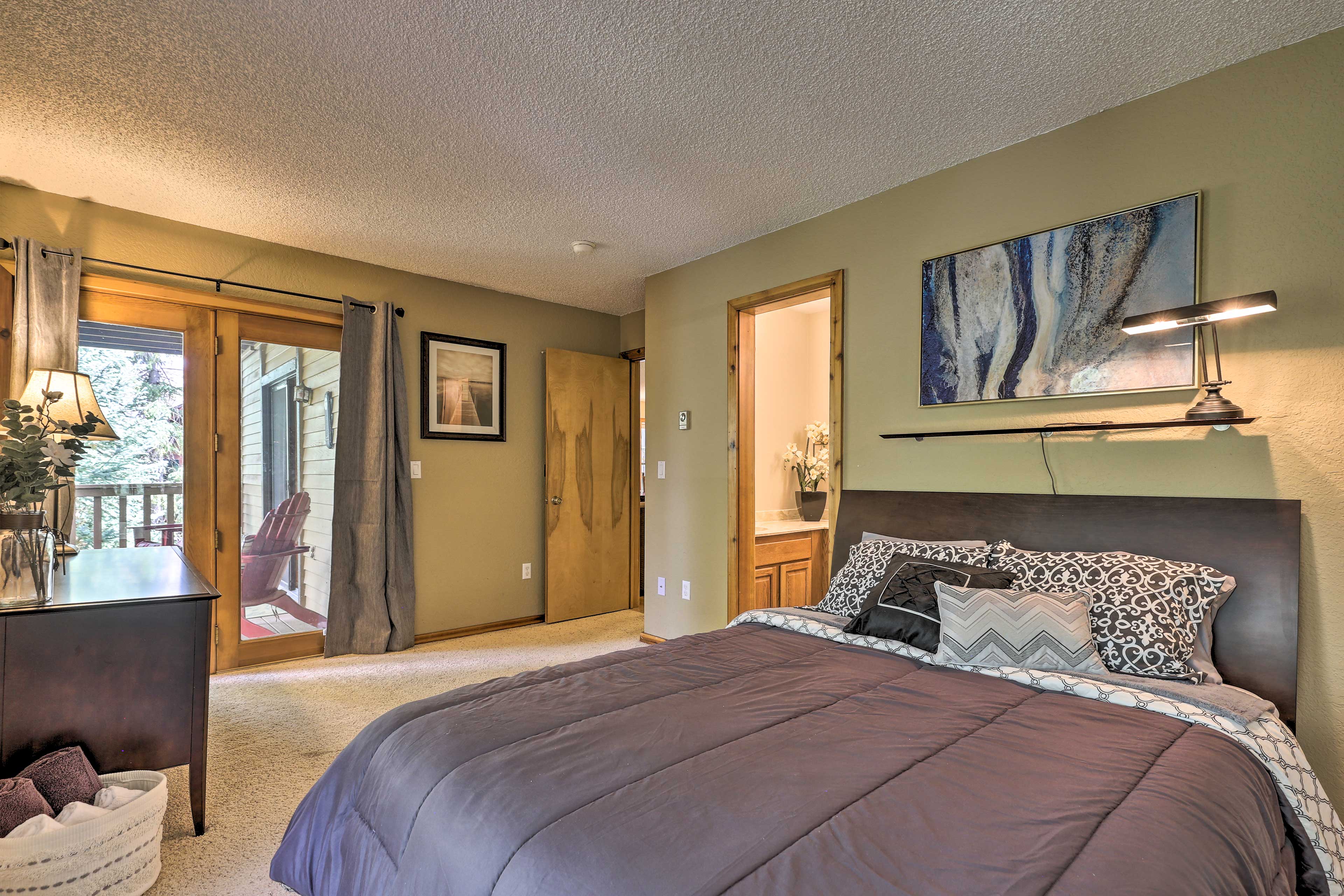 The bedroom boasts a new mattress, an en-suite bath, & private deck access.