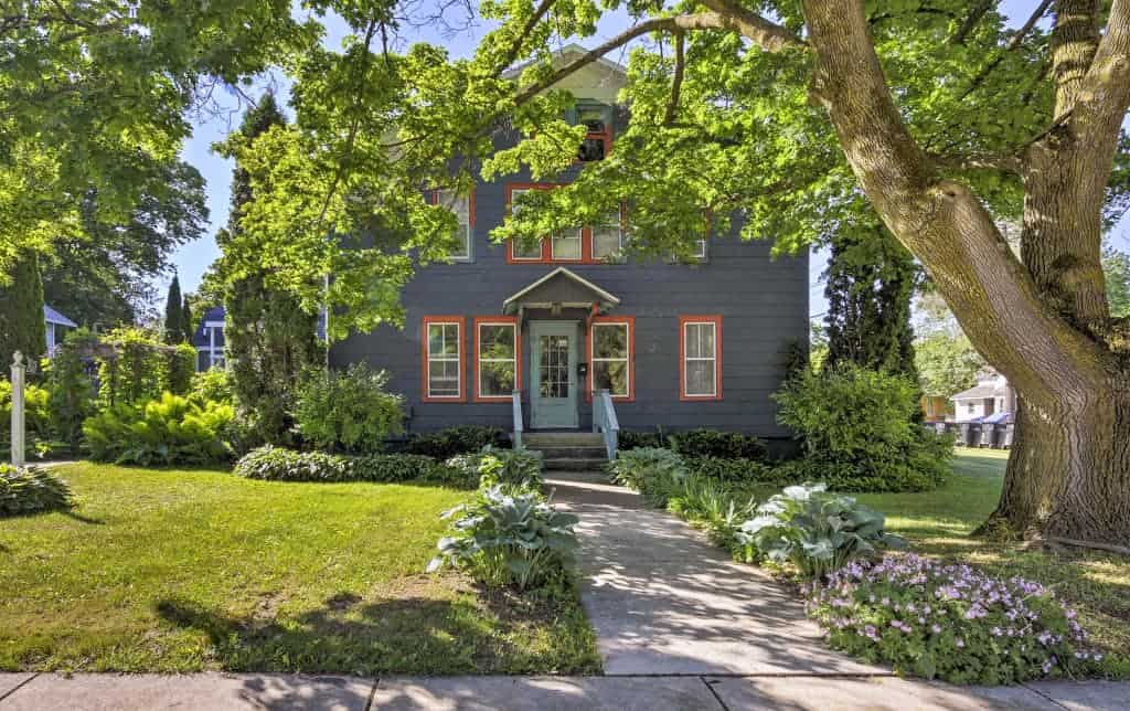 Red, white, and blue coastal farmhouse in Sturgeon Bay, Wisconsin with lush front lawn