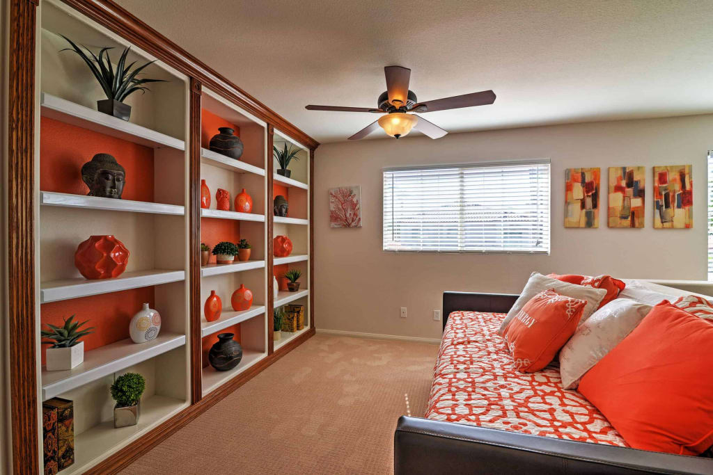 Bedroom with pops of orange color and minimalist bookshelf decor