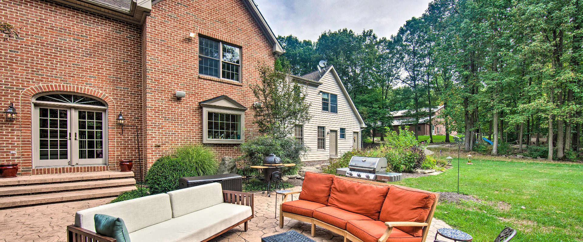 Photo of the backyard patio of a vacation rental in Atglen, PA that includes a grill, smoker, furniture, and barn in the distance.