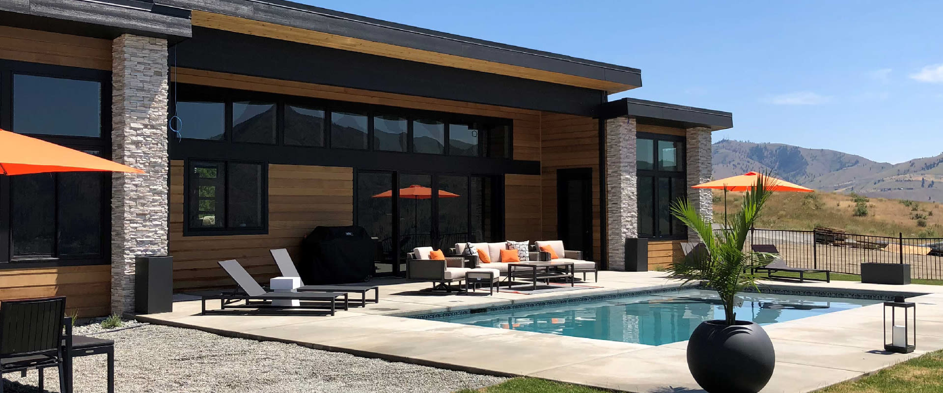 Luxury modern home with a patio and pool surrounded by patio furniture and views of the Cascade Mountains