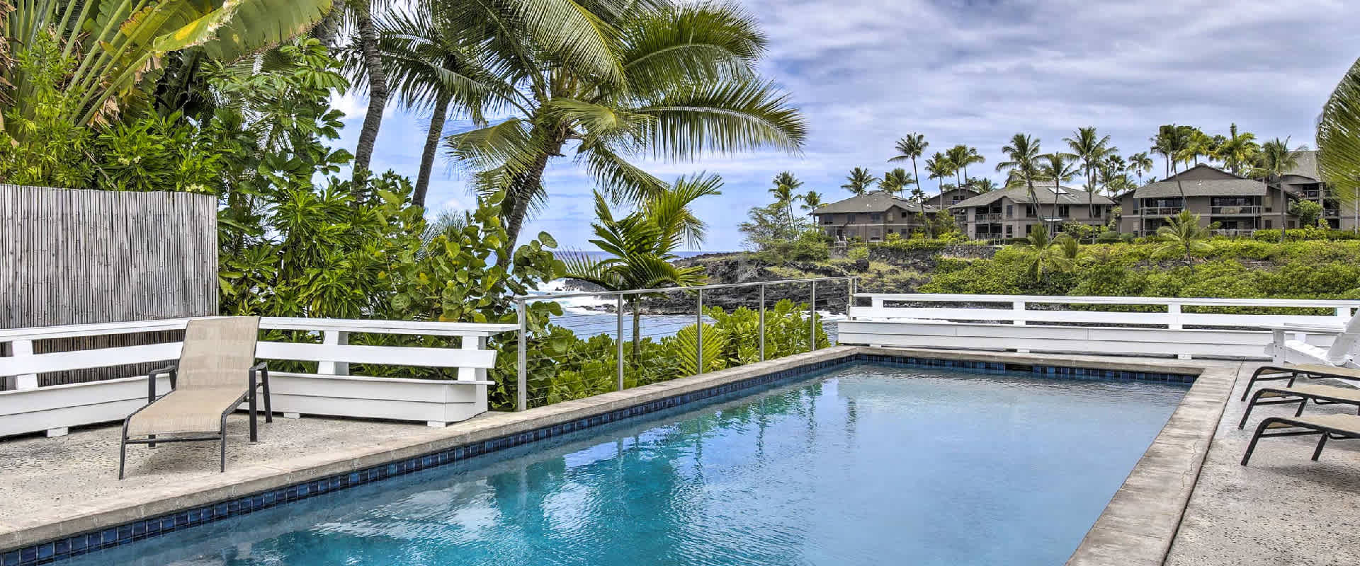 Private deck and pool overlooking Keauhou Bay, surrounded by palm trees and tropical plans