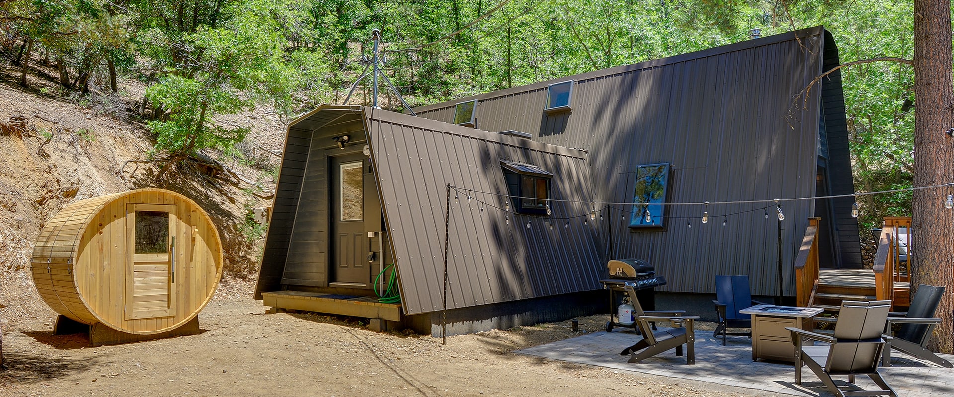 Exterior view of "The Hygge Hideaway" in Prescott, AZ with angular architecture, a barrel sauna, and fire pit.