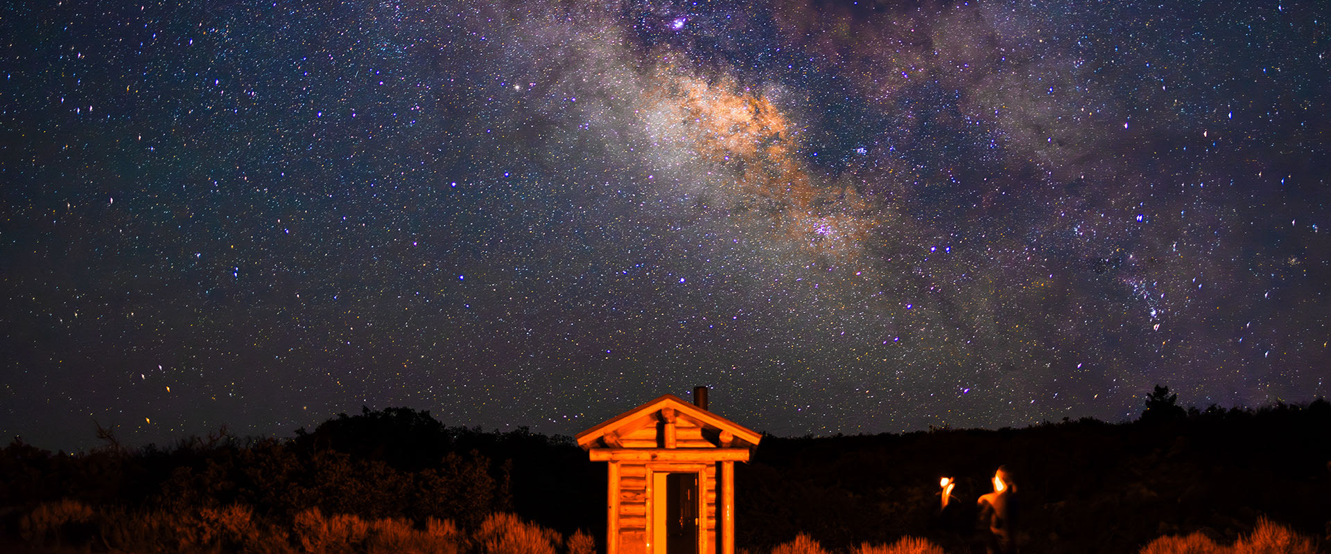 Photo of a small wooden structure lit against the night sky with views of The Milky Way near Black Canyon of the Gunnison National Park in Colorado.