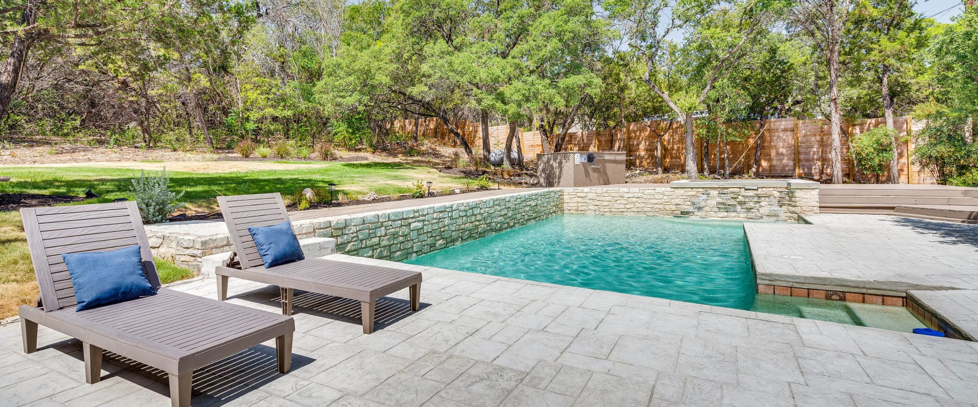 Two lounge chairs next to an outdoor pool on a sunny day