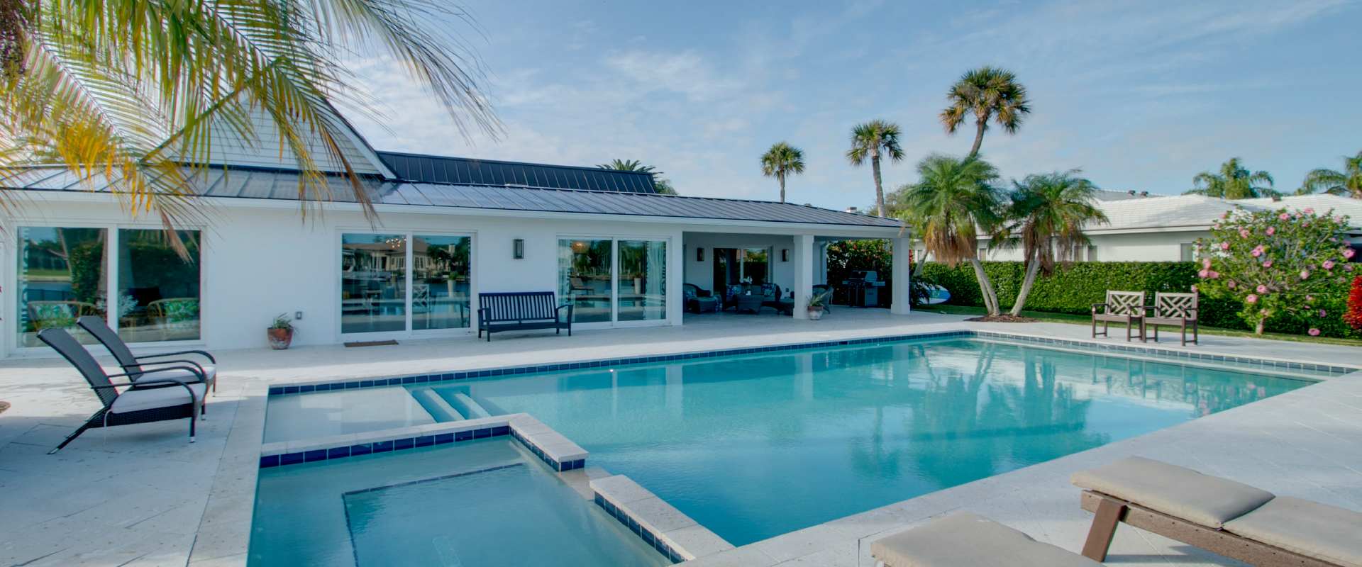 Photo of a lavish backyard pool in Vero Beach, surrounded by lounge chairs and palm trees.