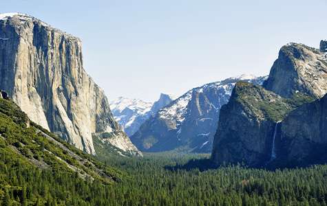 Scenie meadows cut between massive rock formations in Yosemite National Park, known as the Yosemite Tunnel View