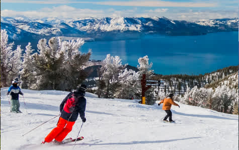 Skiers on the slopes at a Lake Tahoe ski resort with views of the lake and mountains