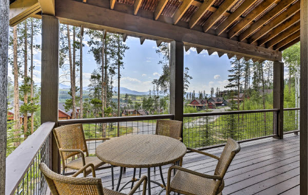 Patio with wicker table and chairs overlooking a mountain view through the trees at a Winter Park, Colorado vacation home