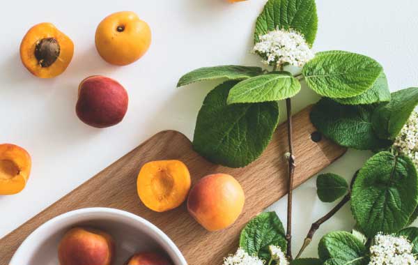 Serving board with flowers and halved peaches strewn about