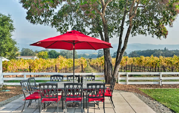 A big glass table sits just feet from a vineyard on the sunny back patio of this Sonoma, California vacation rental.