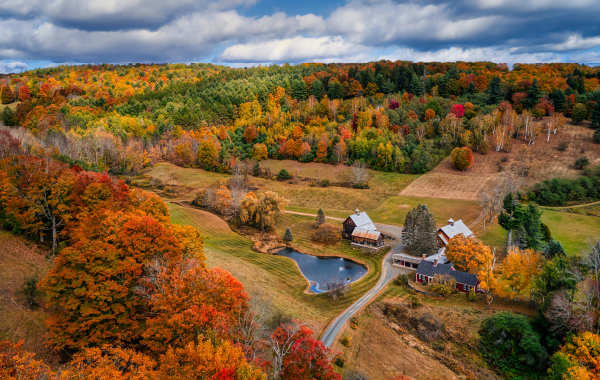 A barn nestled in a valley with sweeping fall foliage views in Vermont