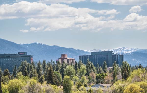 Distant view of Lake Tahoe skyline near lake with snowtopped mountains in the distance and cloudy blue sky