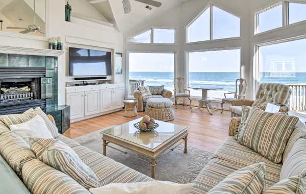 Interior living room space with flat-screen TV, fireplace, and large windows overlooking the ocean