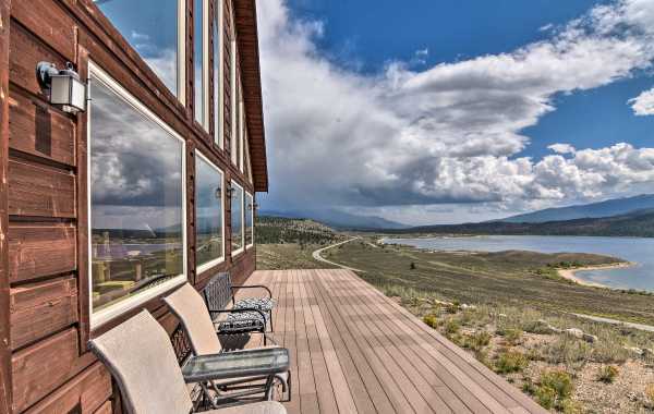 Deck chairs facing the waterfront from a lake house patio with mountain views and big blue skies