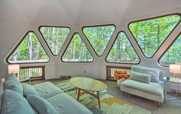 Inside a unique vacation rental with triangular windows and modern furniture with trees outside in the background