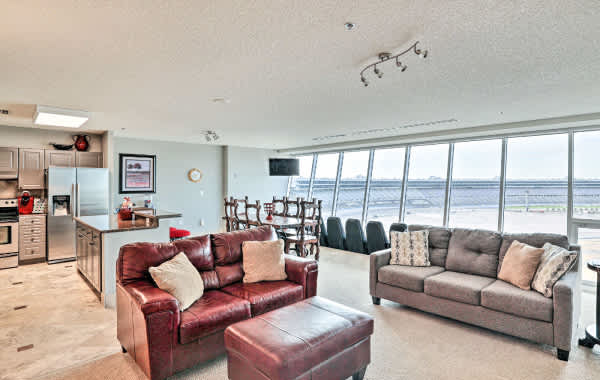 Vacation rental living room and kitchen area with floor-to-ceiling windows looking out over the Texas Motor Speedway in Fort Worth, TX