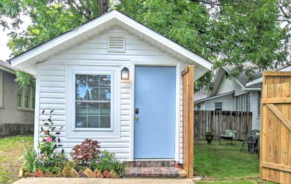 Image of a tiny house vacation rental in Hot Springs, AR with an open gate leading into the backyard with patio furniture.