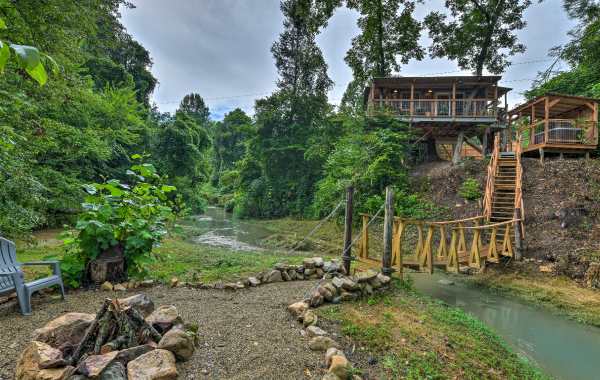 Image of a vacation rental treehouse with a bridge leading to a fire pit in the foreground